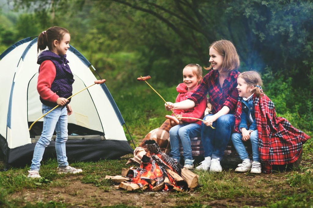 family partaking in outdoor activities, including a bonfire and camping