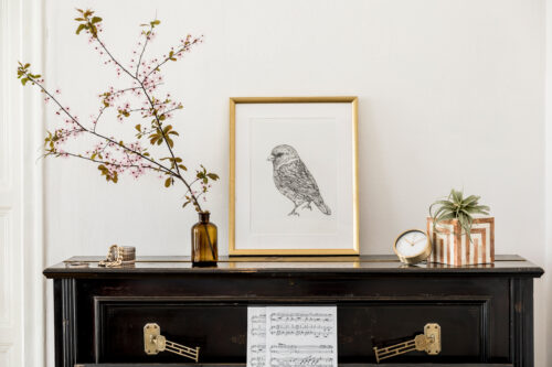 interior design - gold framed bird art, vase with flowers, black furniture. Followtheflow© Shutterstock