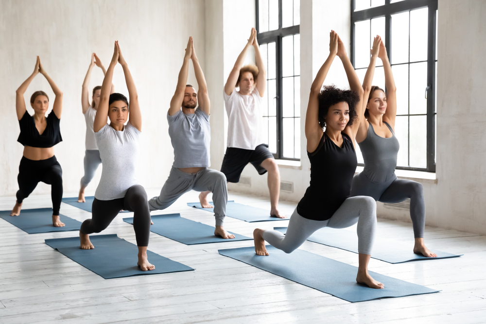 Community yoga class of adults holding pose together ©fizkes