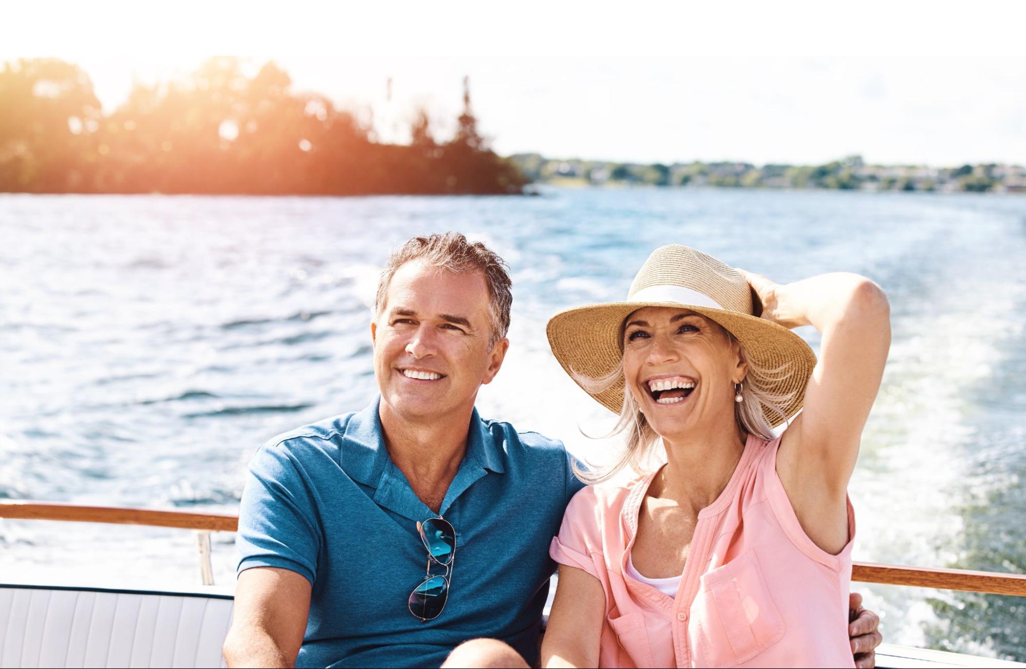 Middle-aged couple smiling on a boat on Lake Lanier. The boat is moving through the water and the woman is holding onto her hat.
©PeopleImages.com - Yuri A