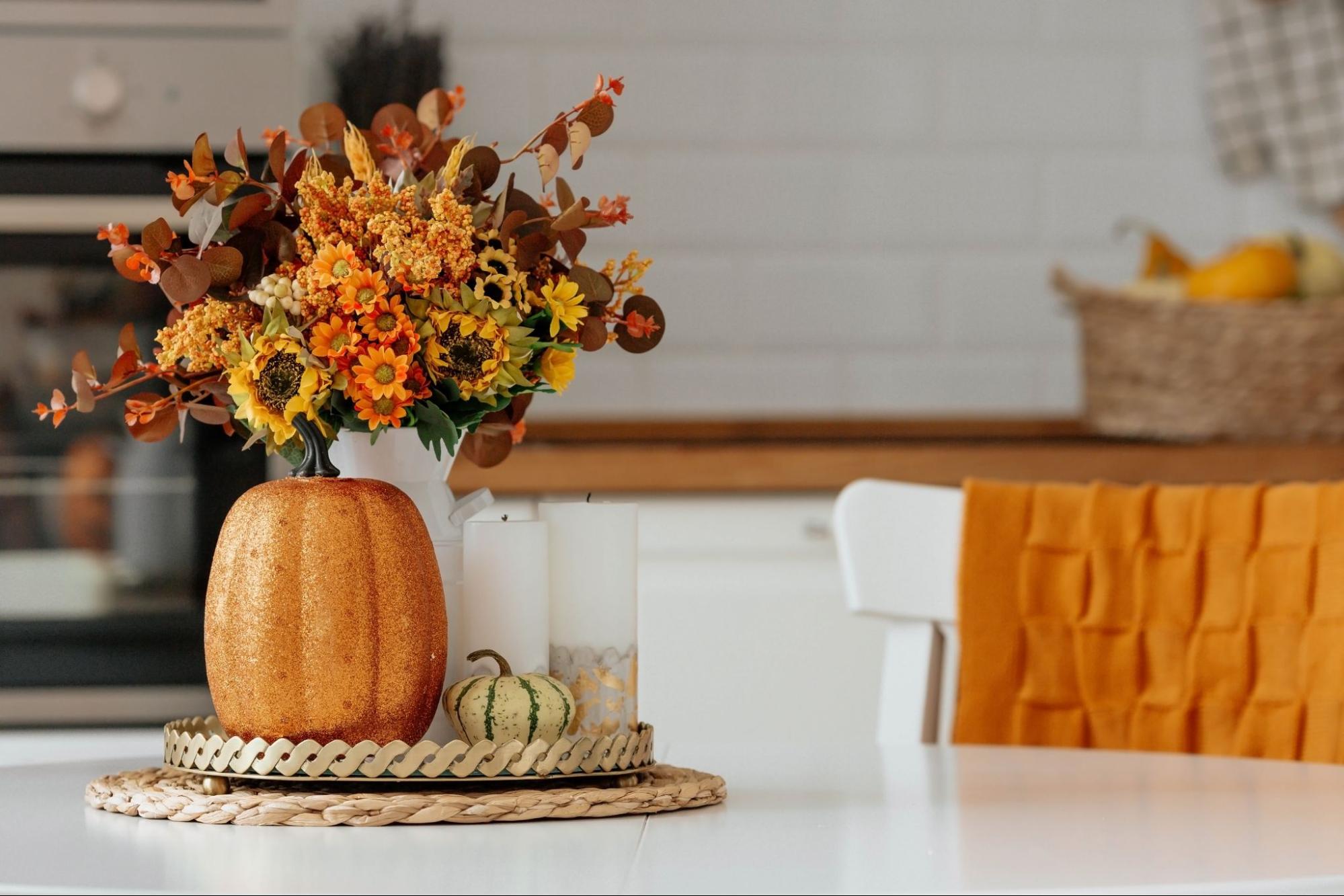 Autumn still-life with pumpkins, candles, and yellow-orange flowers in a vase on a kitchen table.
©PhotoJuli86
