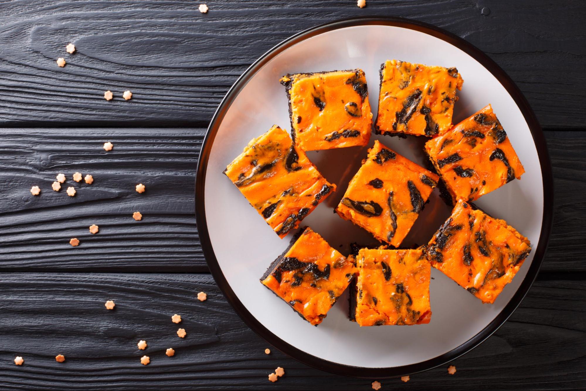 Halloween cheesecake swirl brownies with orange and brown layers on a plate ©Sergii Koval