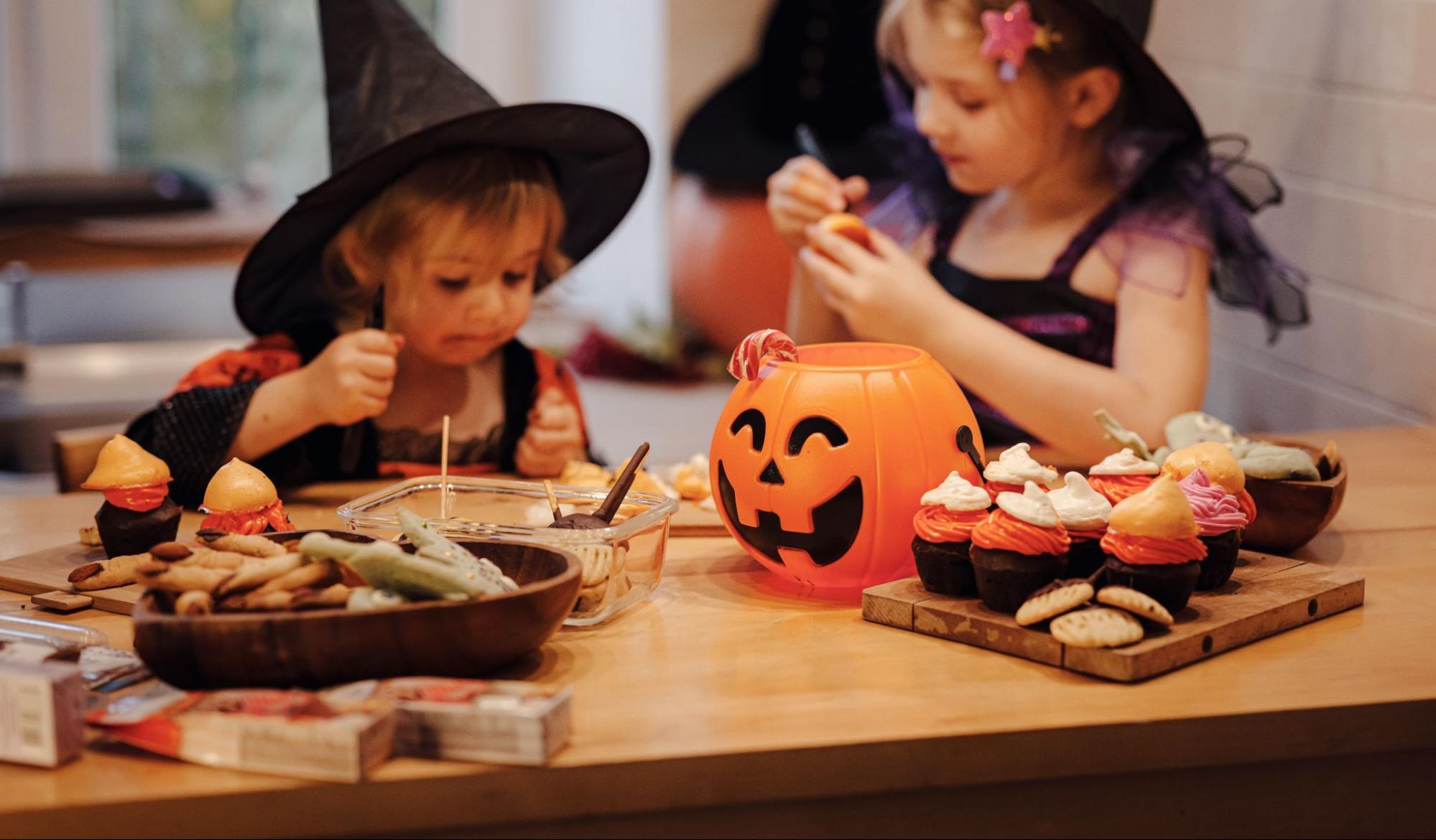 Two girls in Halloween costumes enjoying treats at a decorated table ©U__Photo