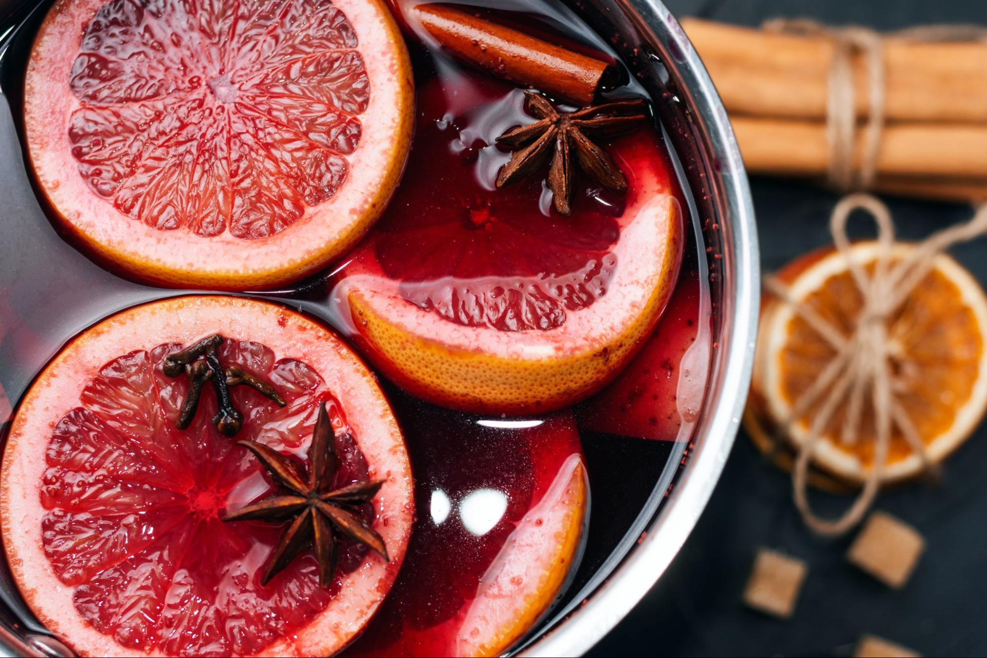Pot of mulled wine with cinnamon sticks, citrus, and star anise on a table
©Andrii Marushchynets