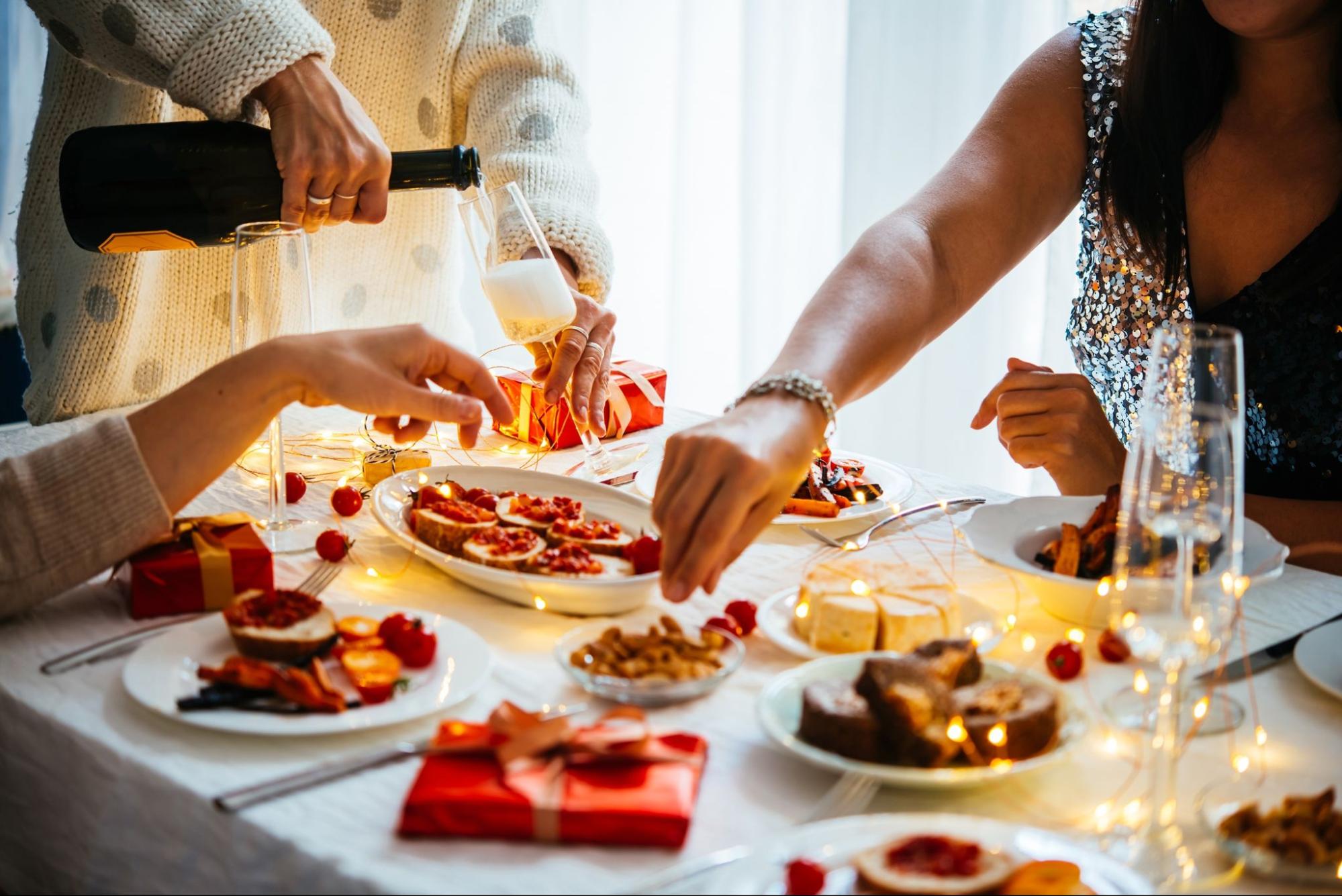 Pouring champagne over a table set with appetizers for a holiday celebration
©fornStudio