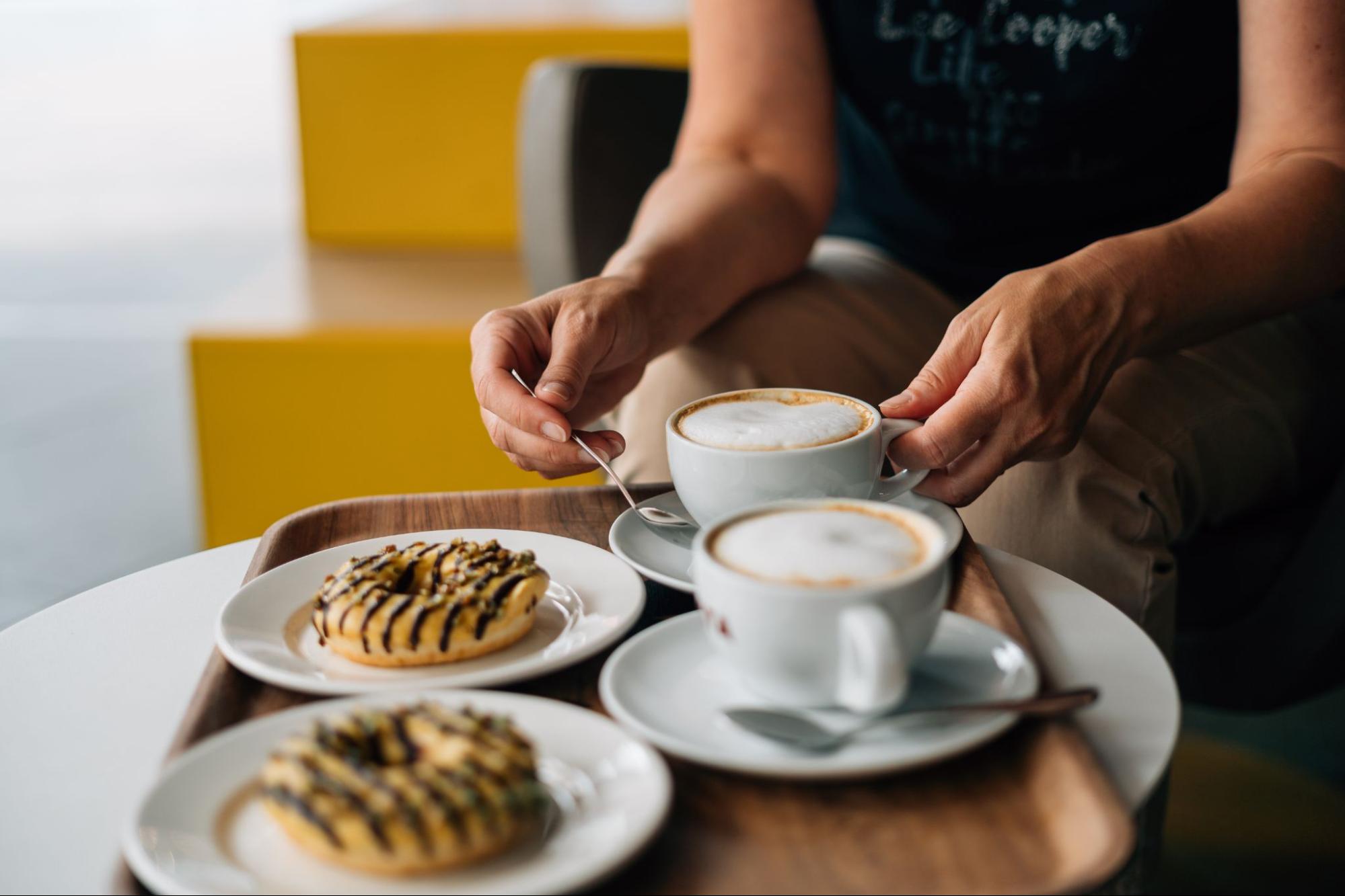 Two lattes and donuts on a cafe table for a cozy winter treat ©Troyan