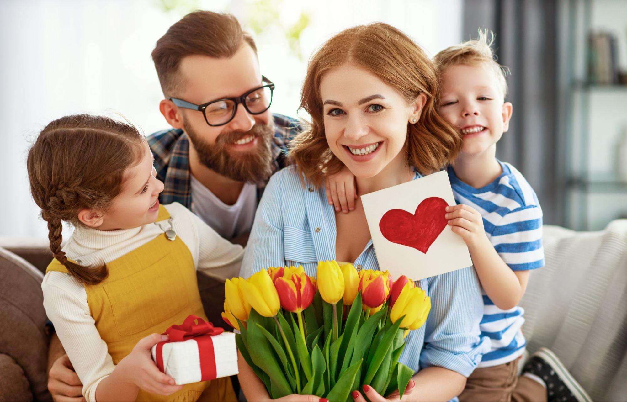 Happy family portrait with mother holding yellow tulips and kids presenting gifts for Mother's Day. ©Evgeny Atamanenko