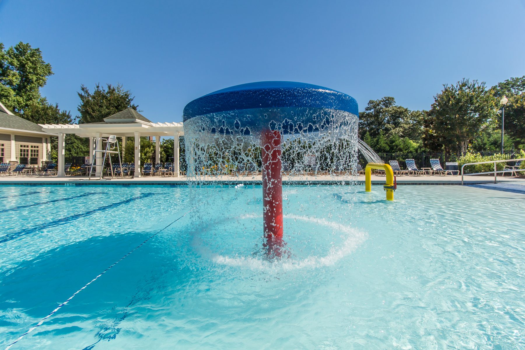 Blue mushroom water fountain feature in a resort-style swimming pool. 