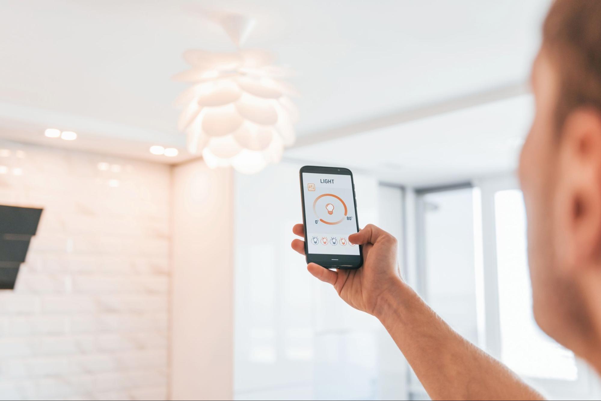 Person using a smartphone app to control smart home lighting. ©Standret