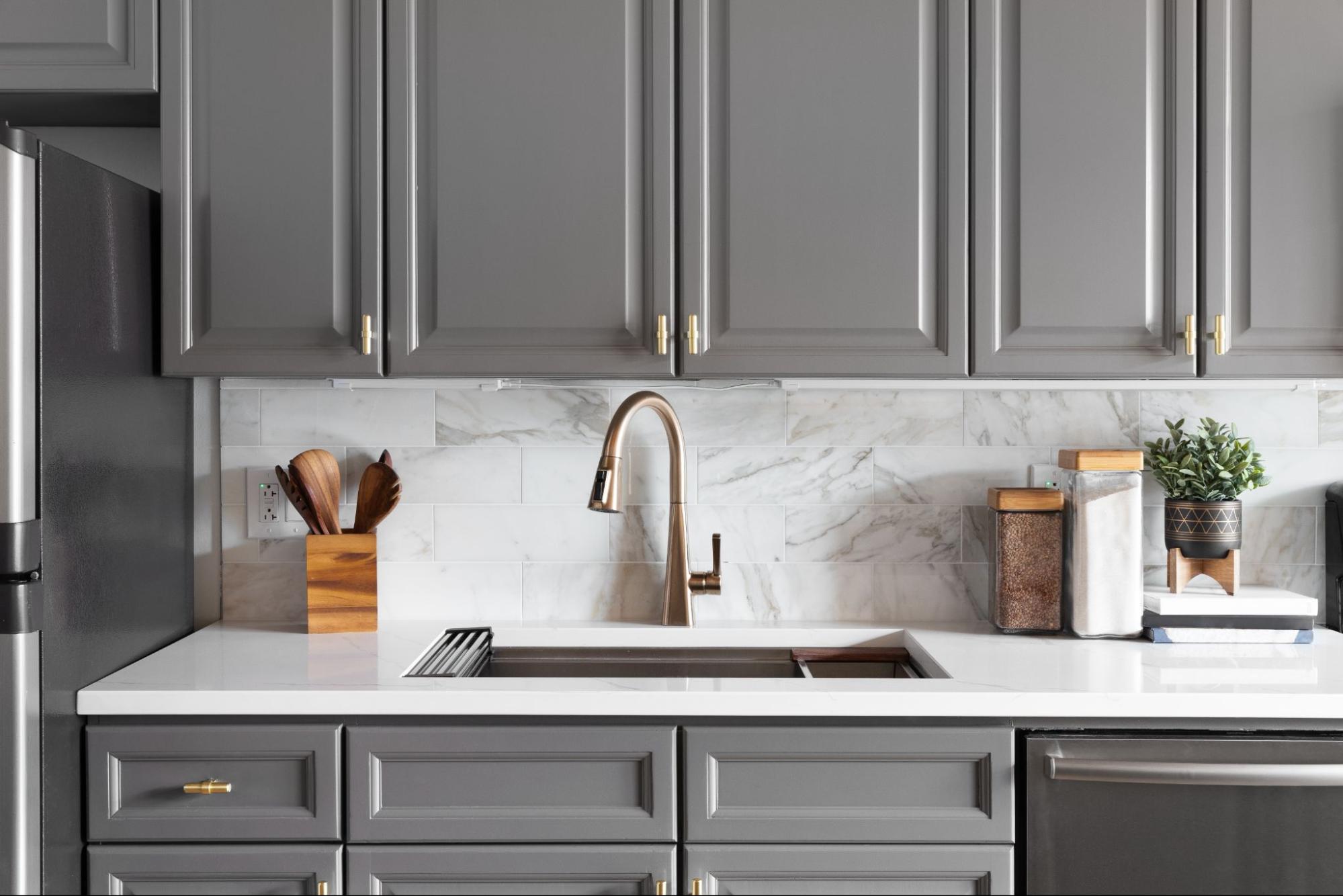 Modern kitchen sink detail featuring grey cabinets and a bronze faucet. ©Joseph Hendrickson